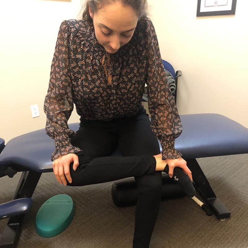 Seated piriformis and glute stretch to relieve pain caused by the piriformis syndrome as show by chiropractor at True Sport Care in Nesconset