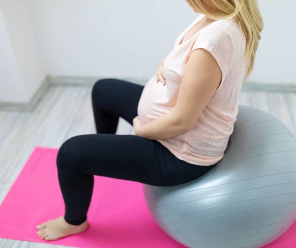 Pregnant woman sitting in a chiropractor’s office during third trimeste