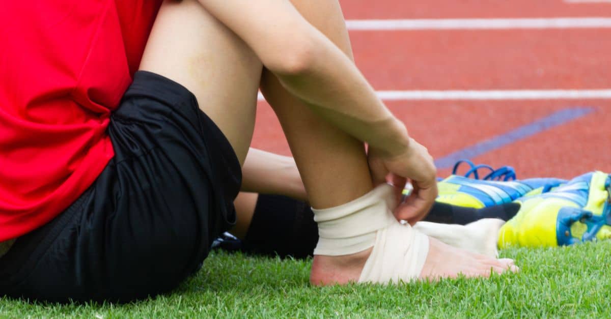 Soccer player applying an ankle brace after suffering an ankle sprain