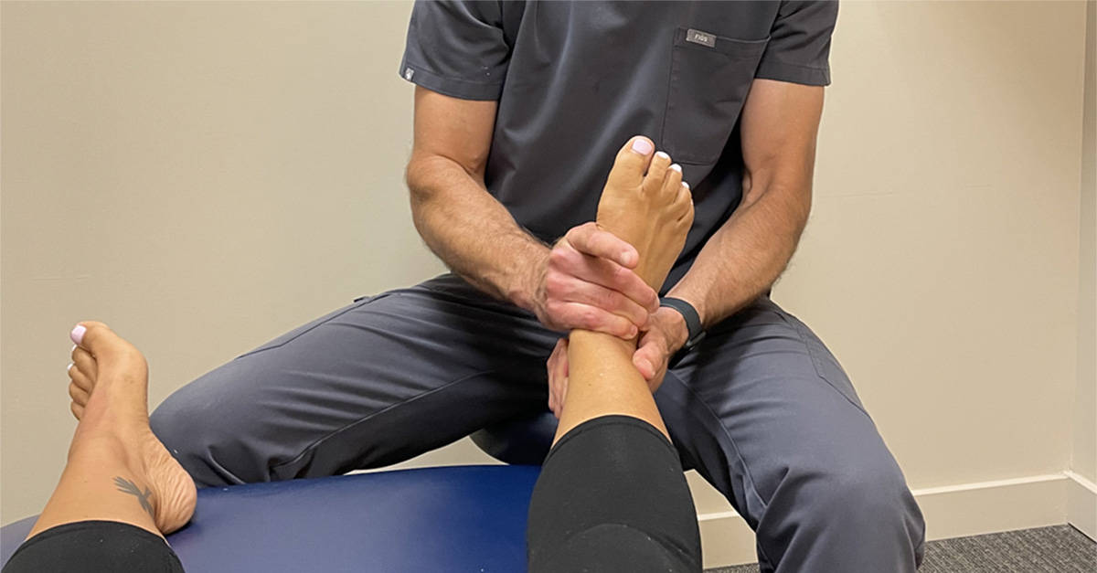 Chiropractor performing ankle joint mobilization for a patient who suffered an ankle sprain