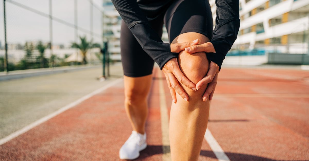 Athlete holding a knee because of the overuse knee injury and pain